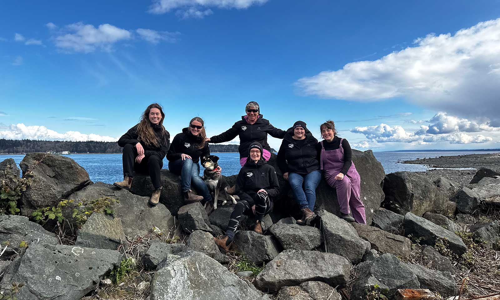mers marine education research society team sitting on rocks with water and sky in background